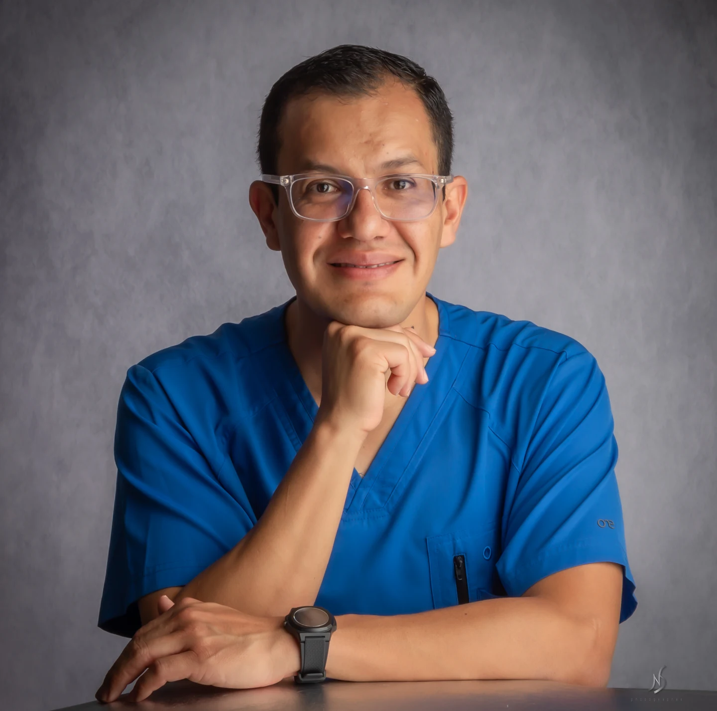 Dr. Julio Sauza con uniforme médico azul.